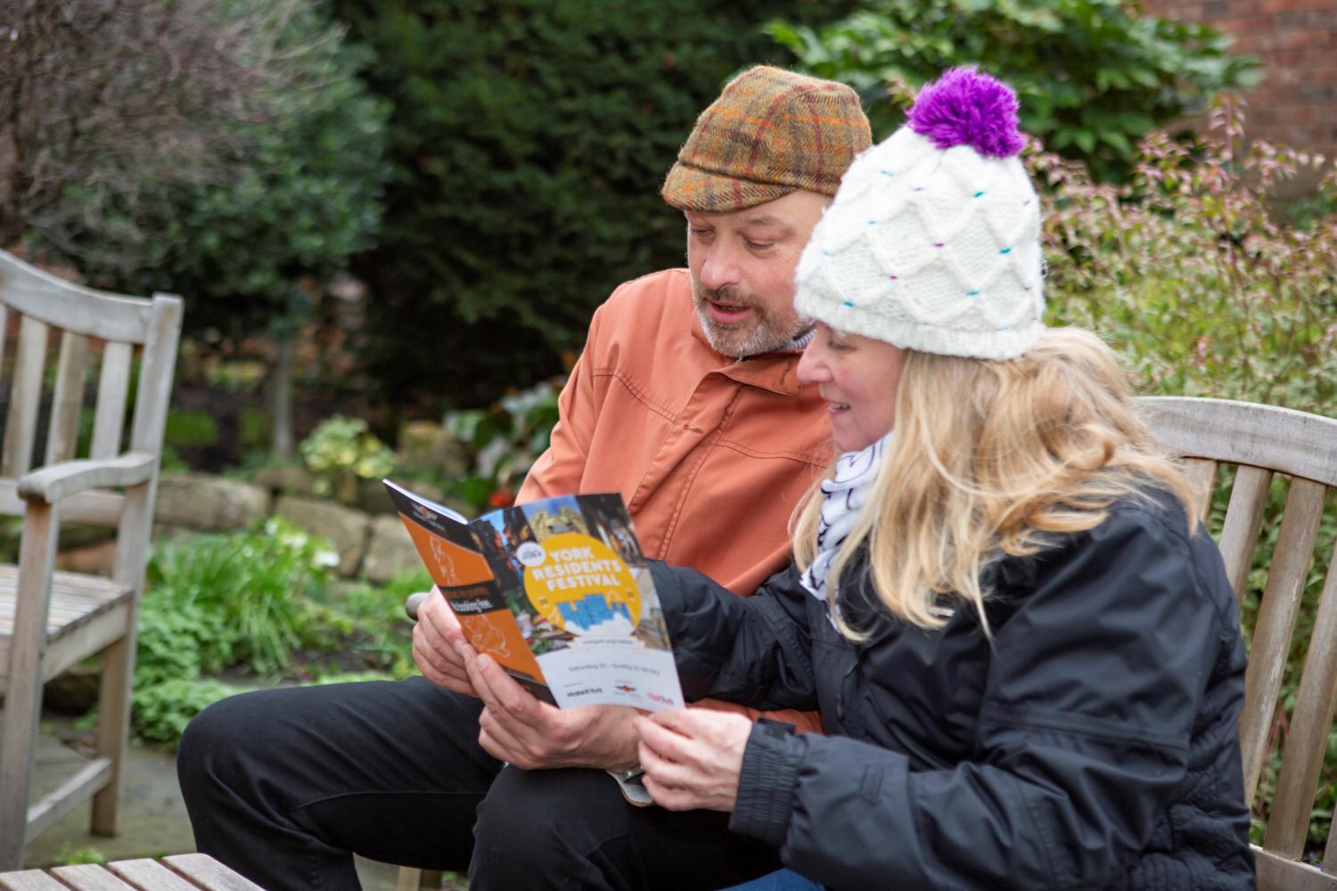 couple sat on a bench reading york residents festival brochure